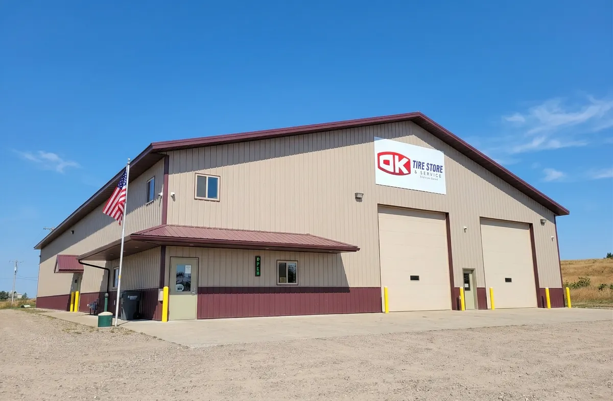 OK Tire Store & Service building in Perham, Minnesota on a clear summer day with an American flag out front